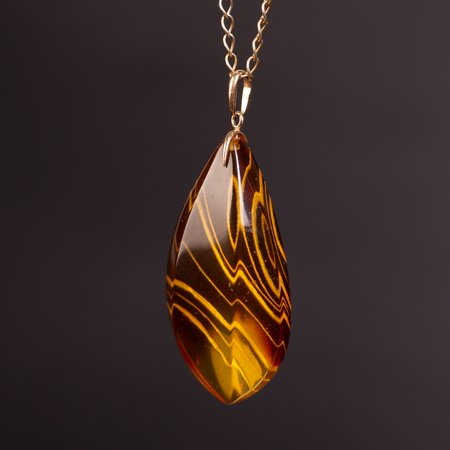 Carved Baltic amber pendant with a gold clasp