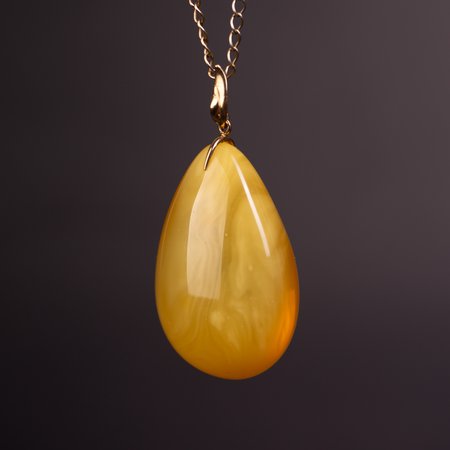 A pendant with a delicate gold chain and a piece of natural honey-colored amber 3